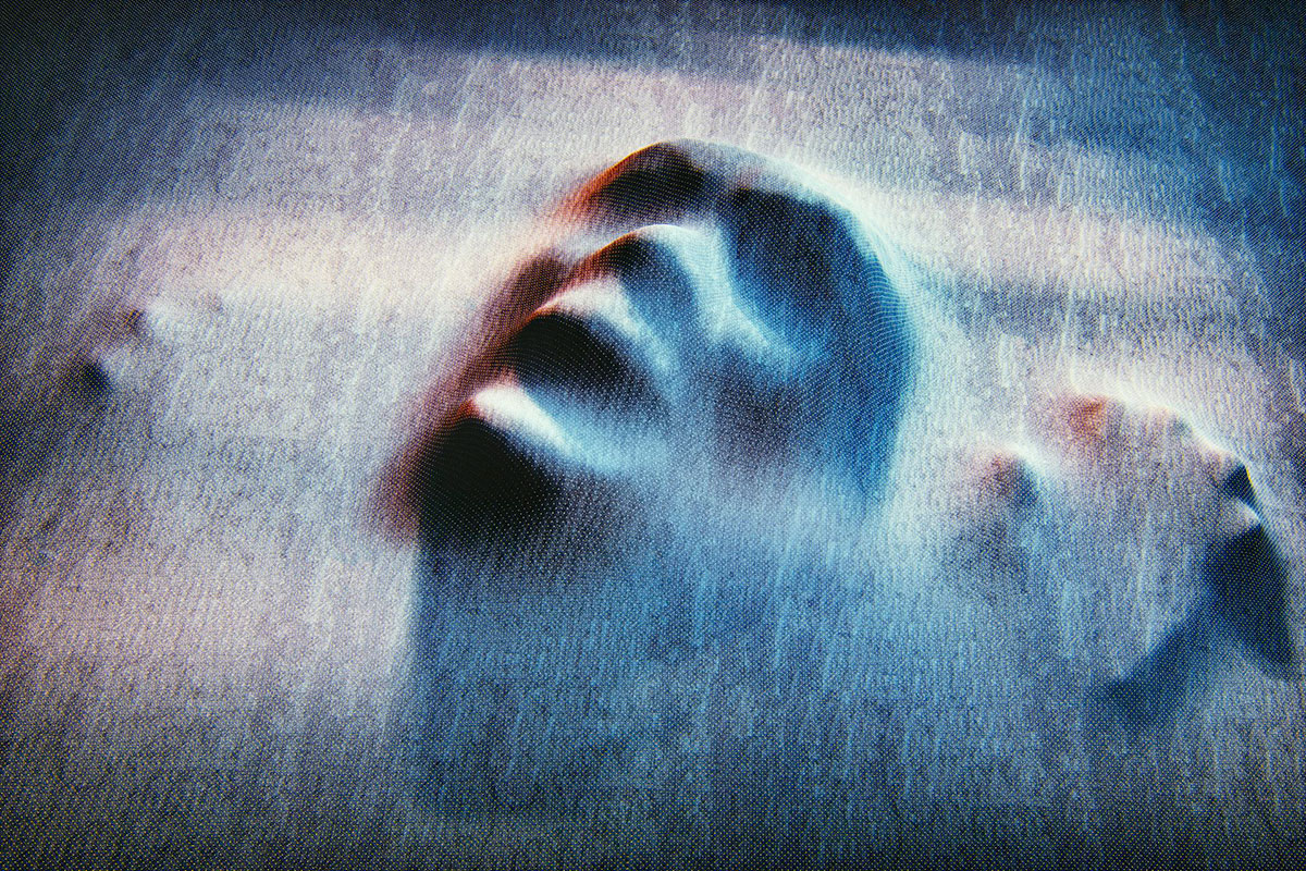 The impression of a face and hands pushes against grey fabric