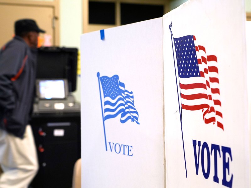 A person is seen walking in the background between voting booths