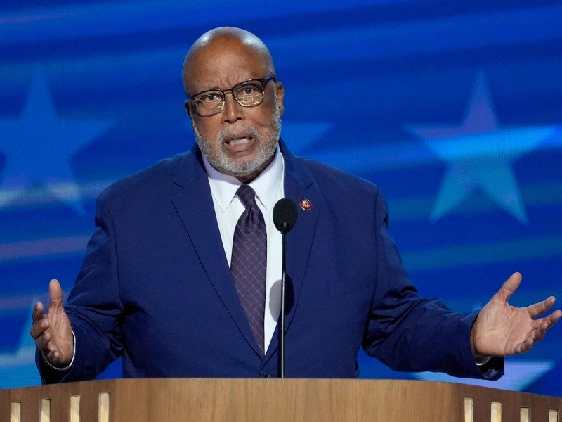 a photo of Bennie Thompson speaking at the DNC with a blue background with large stars behind him