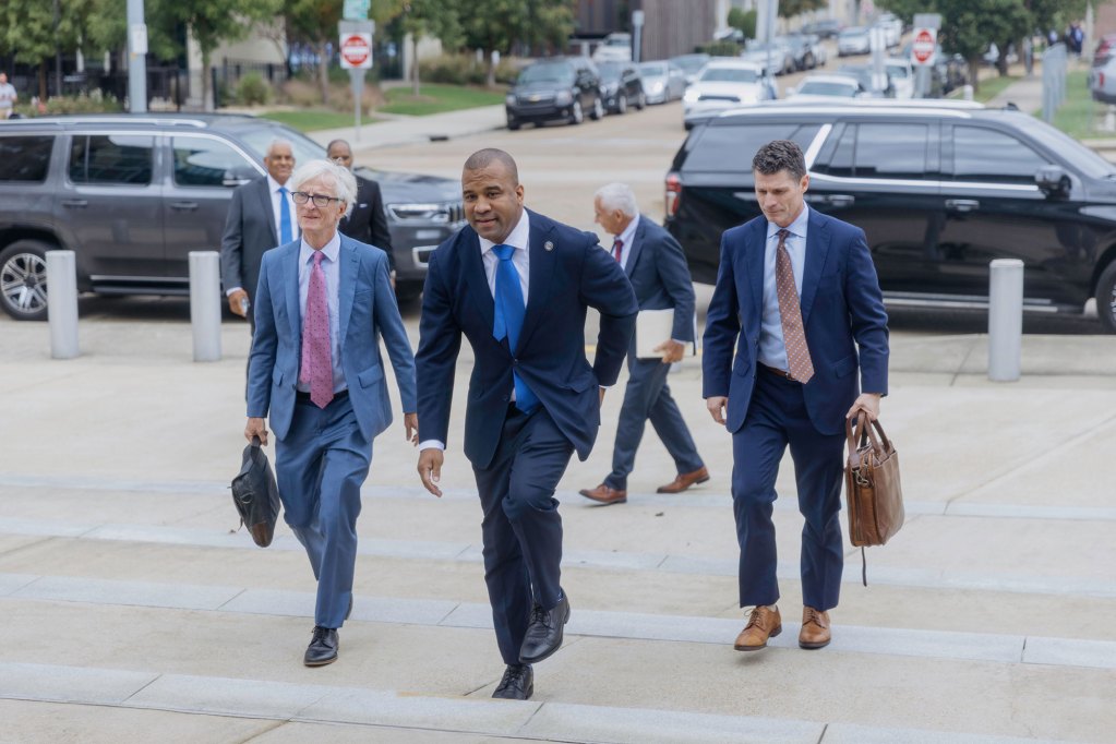 A man in a suit walking up steps with other men in suits behind him