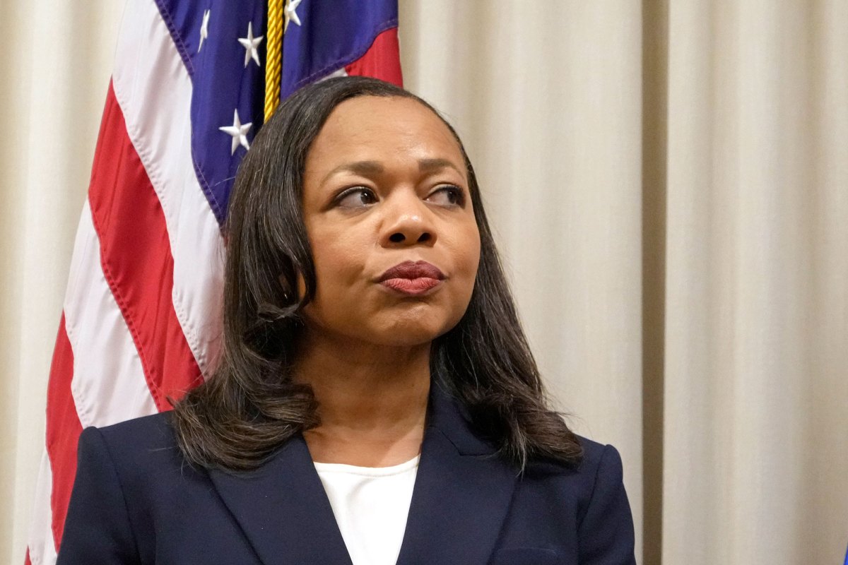 A woman stands in front of a US flag