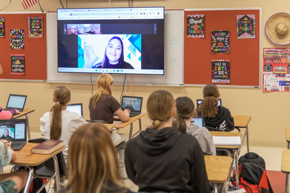 Students learning with a virtual teacher projected in the front of the classroom