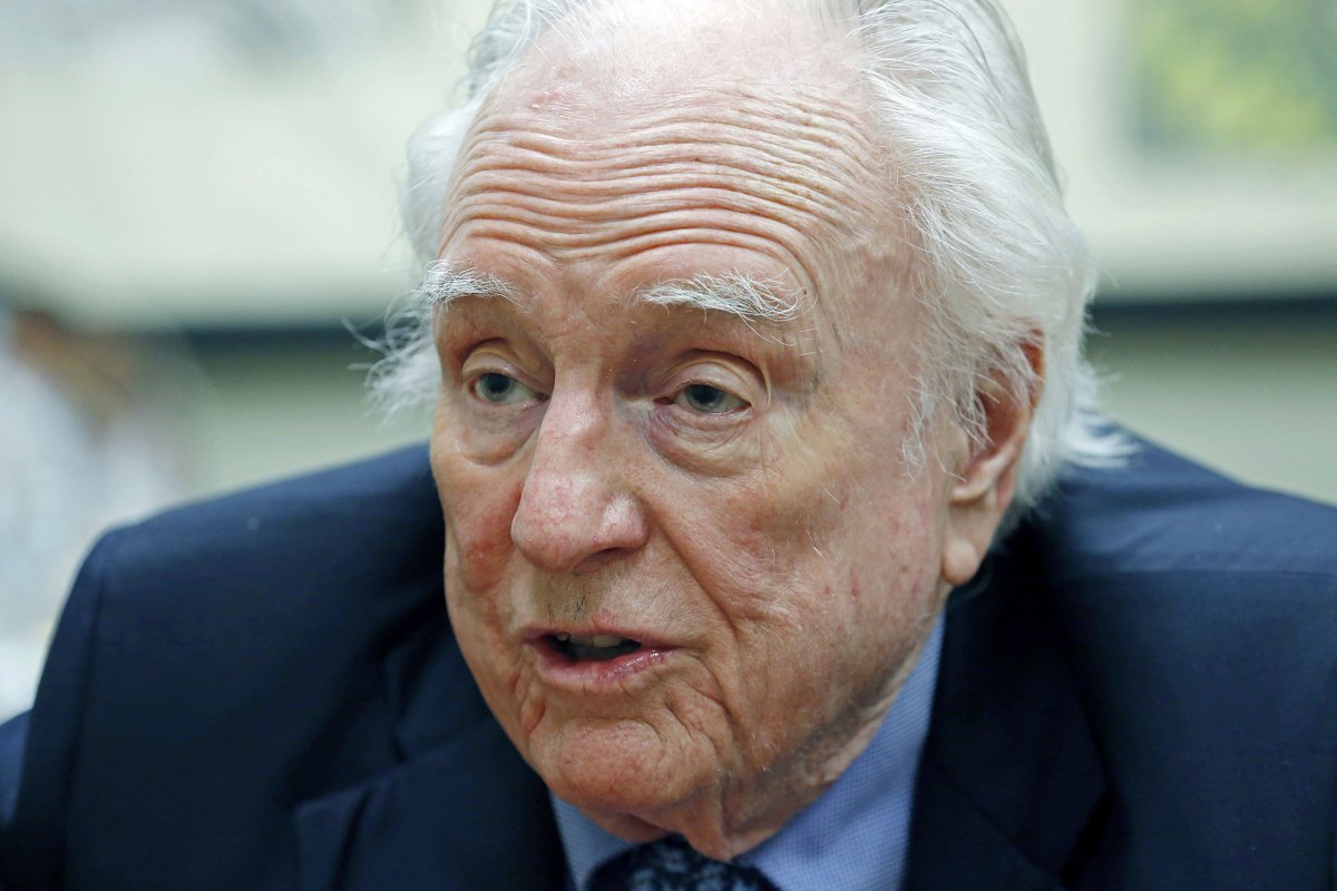 A closeup of an older man in a navy suit