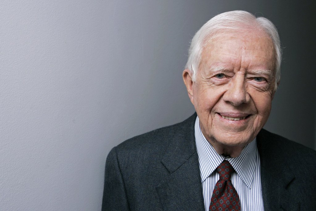 A portrait of Jimmy Carter in suit and tie, against a plain grey wall
