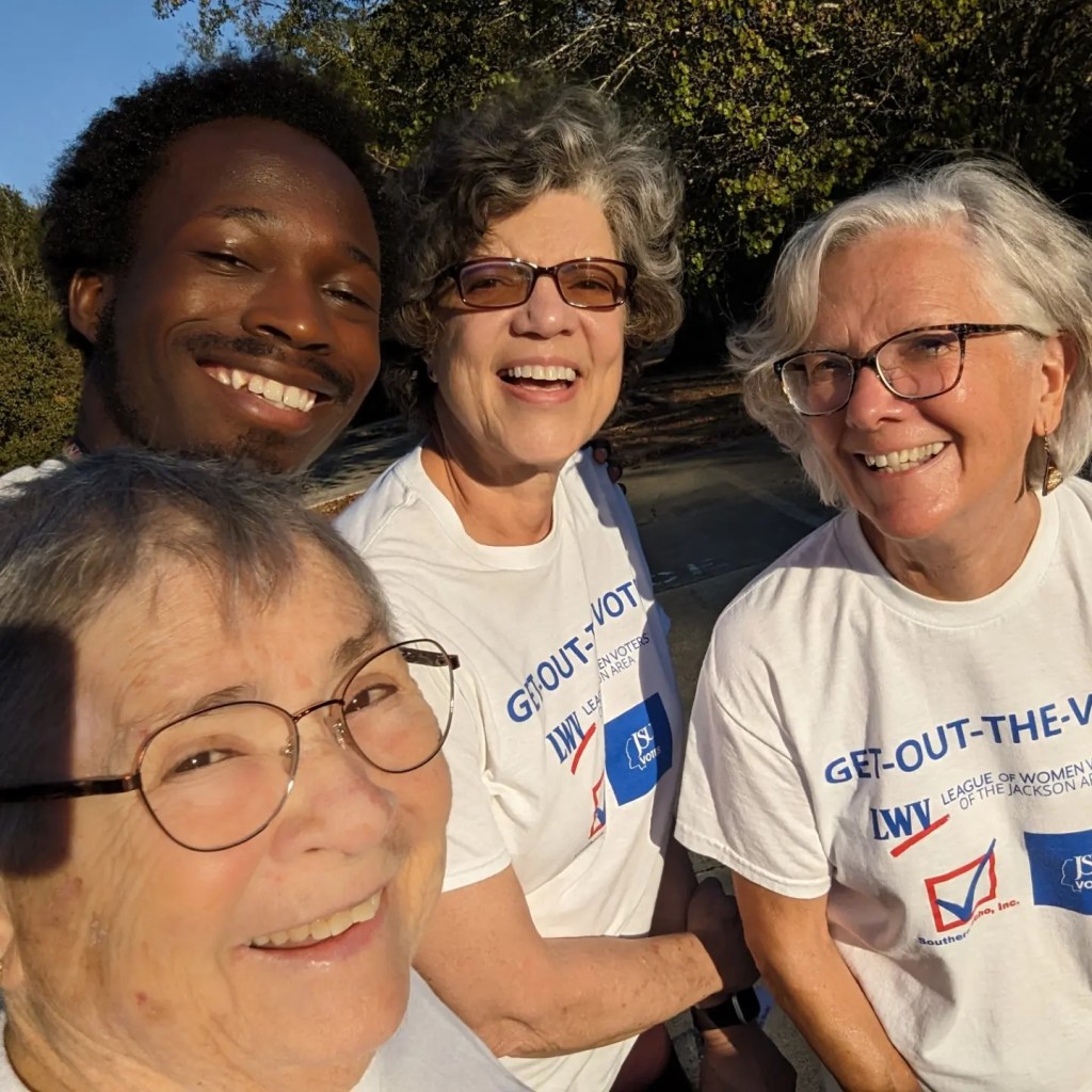 Four people in white "Get out the Vote" tshirts smile for the camera