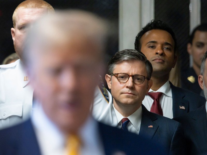 U.S. Speaker of the House Mike Johnson, center, and businessman Vivek Ramaswamy listen as former President Donald Trump, left, talks with reporters