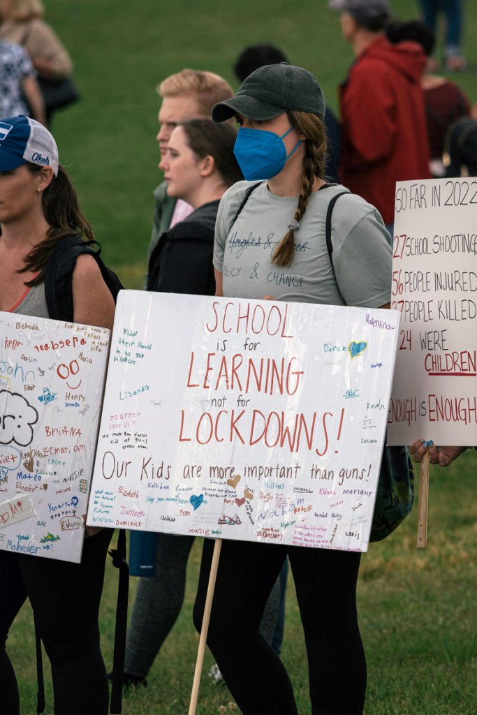 People at a rally. The main sign reads "School is for Learning Not for Lockdowns"