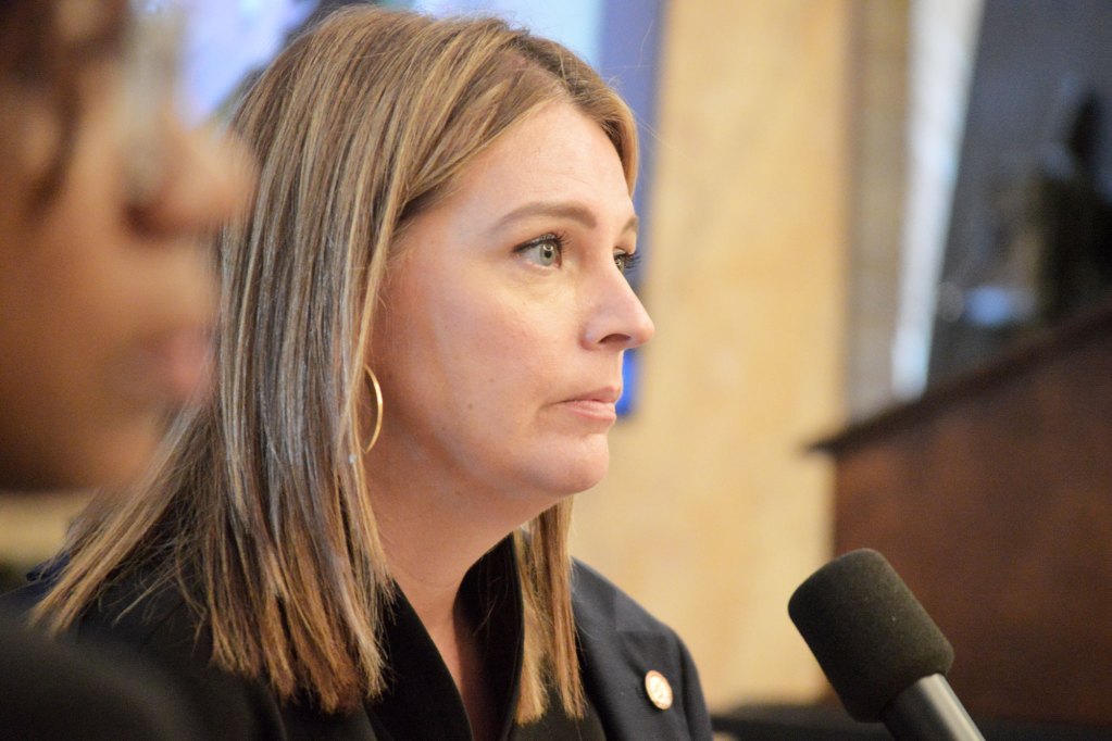 A closeup of Shanda Yates seated in a courtroom with a microphone in front of her