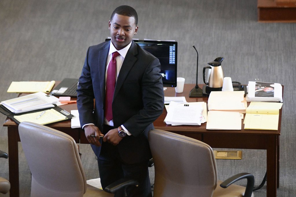 A man in a suit stands at a courtroom table