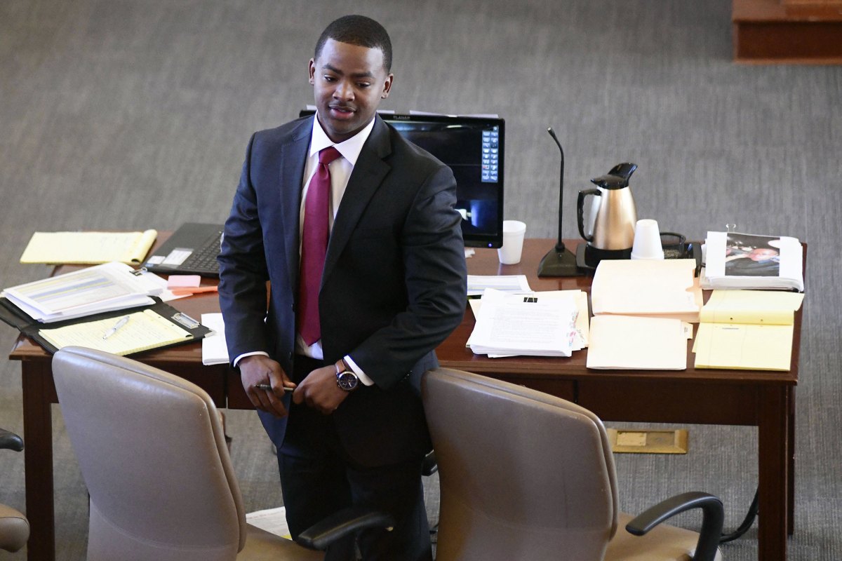 A man in a suit stands at a courtroom table