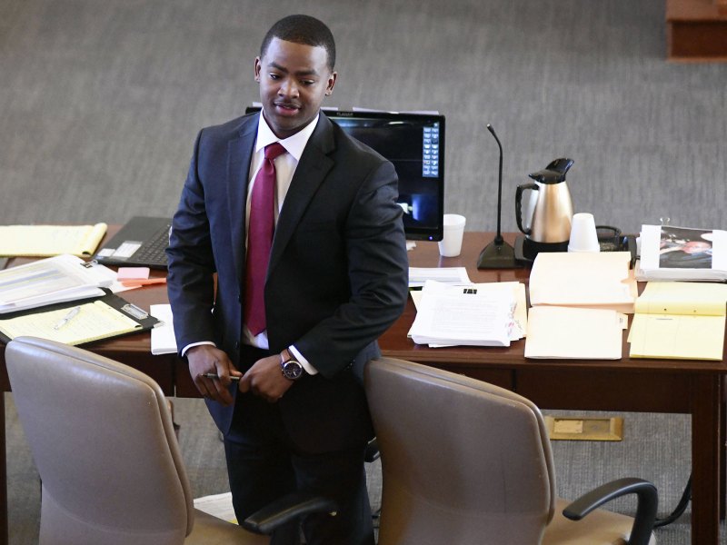A man in a suit stands at a courtroom table