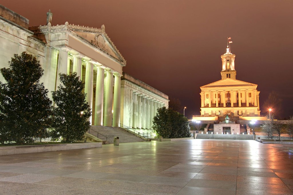 Two large white buildings with columns, on two sides of a large plaza