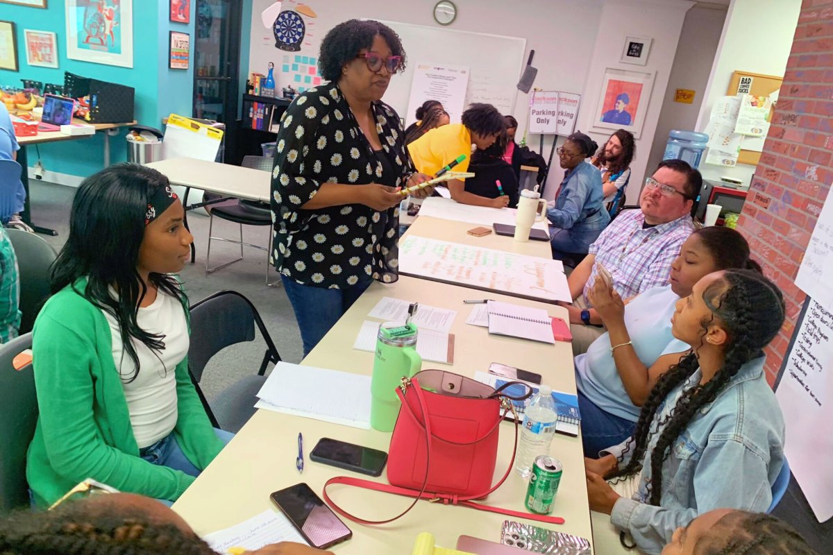 Torsheta Jackson standing at table talking to Youth Media Project and Mississippi Free Press journalists