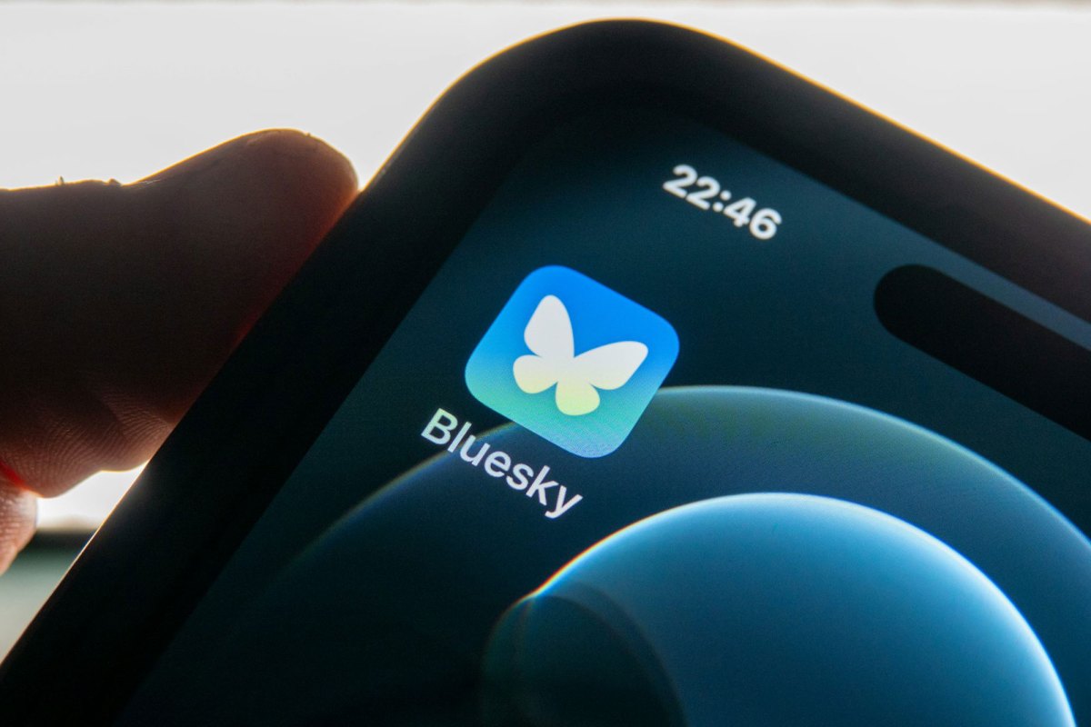 A picture of a phone in someone's hand, with an app icon for Bluesky visible