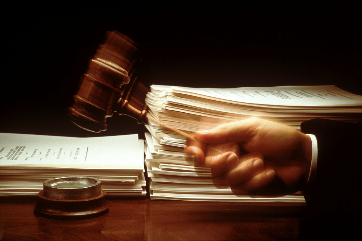 A judge's hand hits a gavel before piles of paperwork