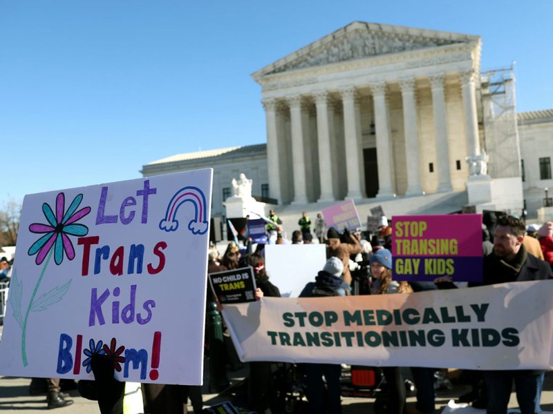 People hold pro and anti trans kids signs outside of the US Supreme Court