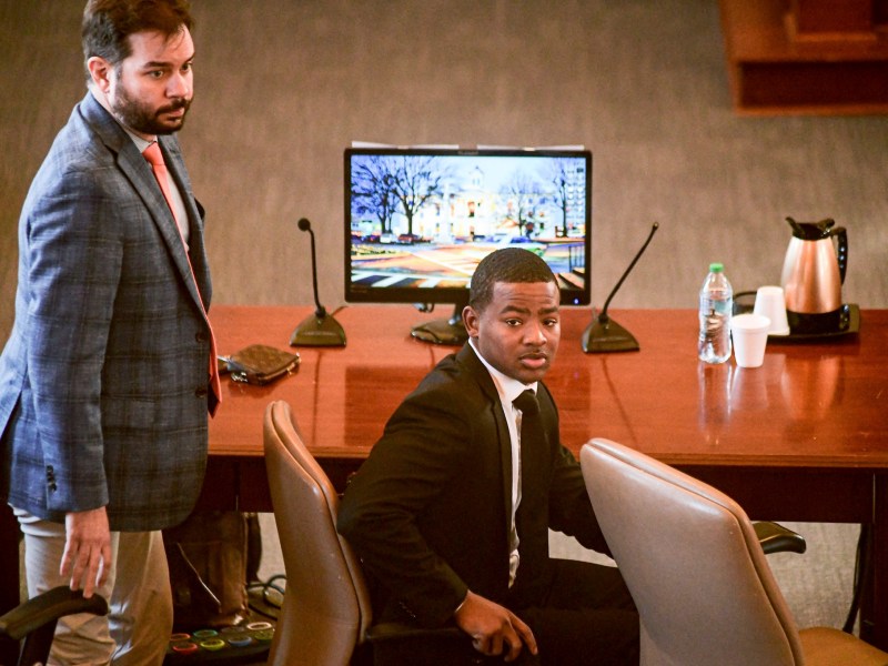 Two men at a court desk look around