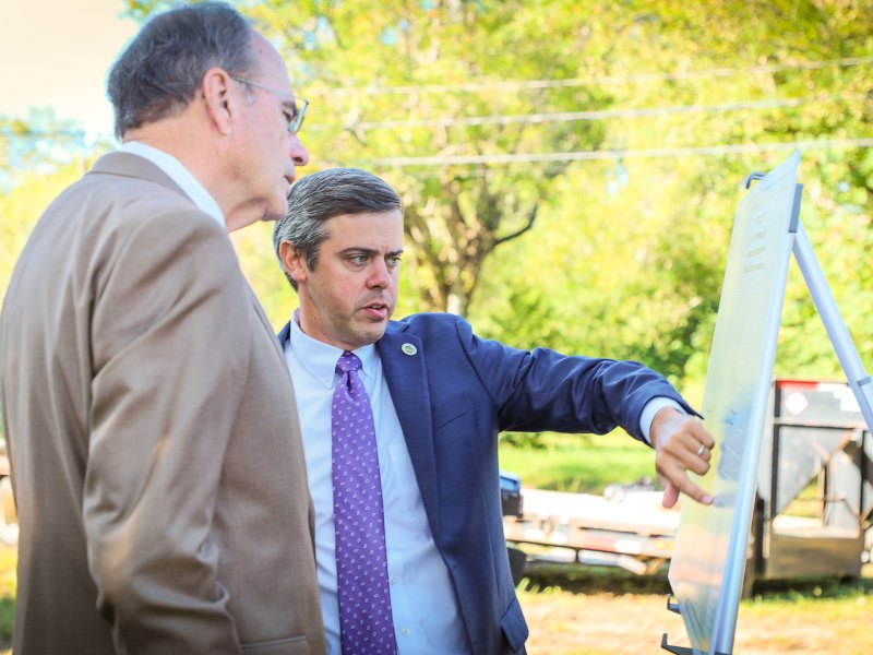 Two men look at an easel outside