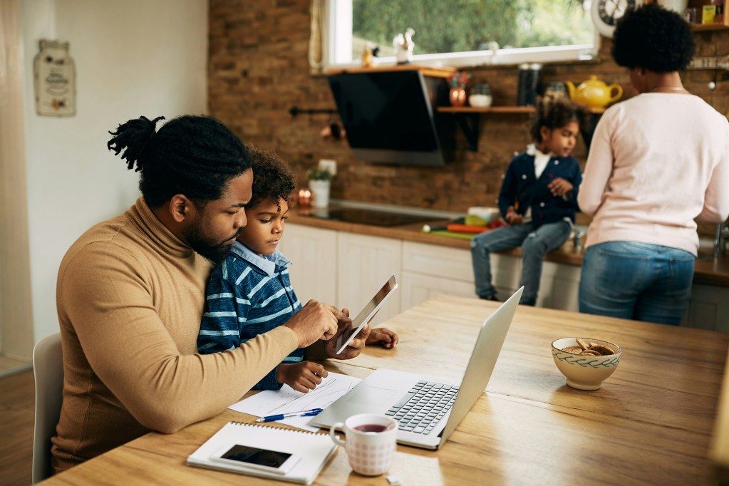 Family at dinner table with children working.