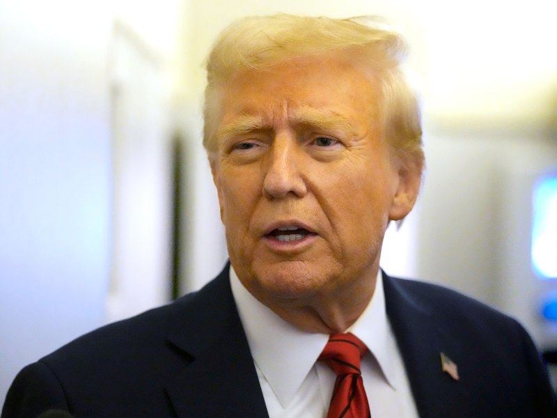 Closeup of a man in a suit and US flag pin on the lapel, speaking