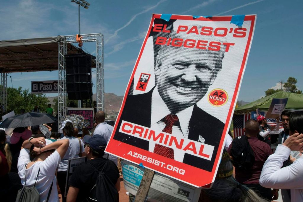 Protestors hold a poster criticizing Donald Trump