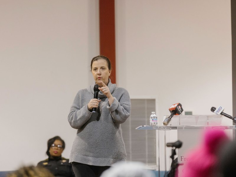 A woman speaking at a Ward 2 community meeting with microphone in hand