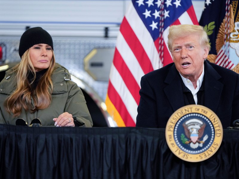 Two people sit outside at a table labeled President of the United States