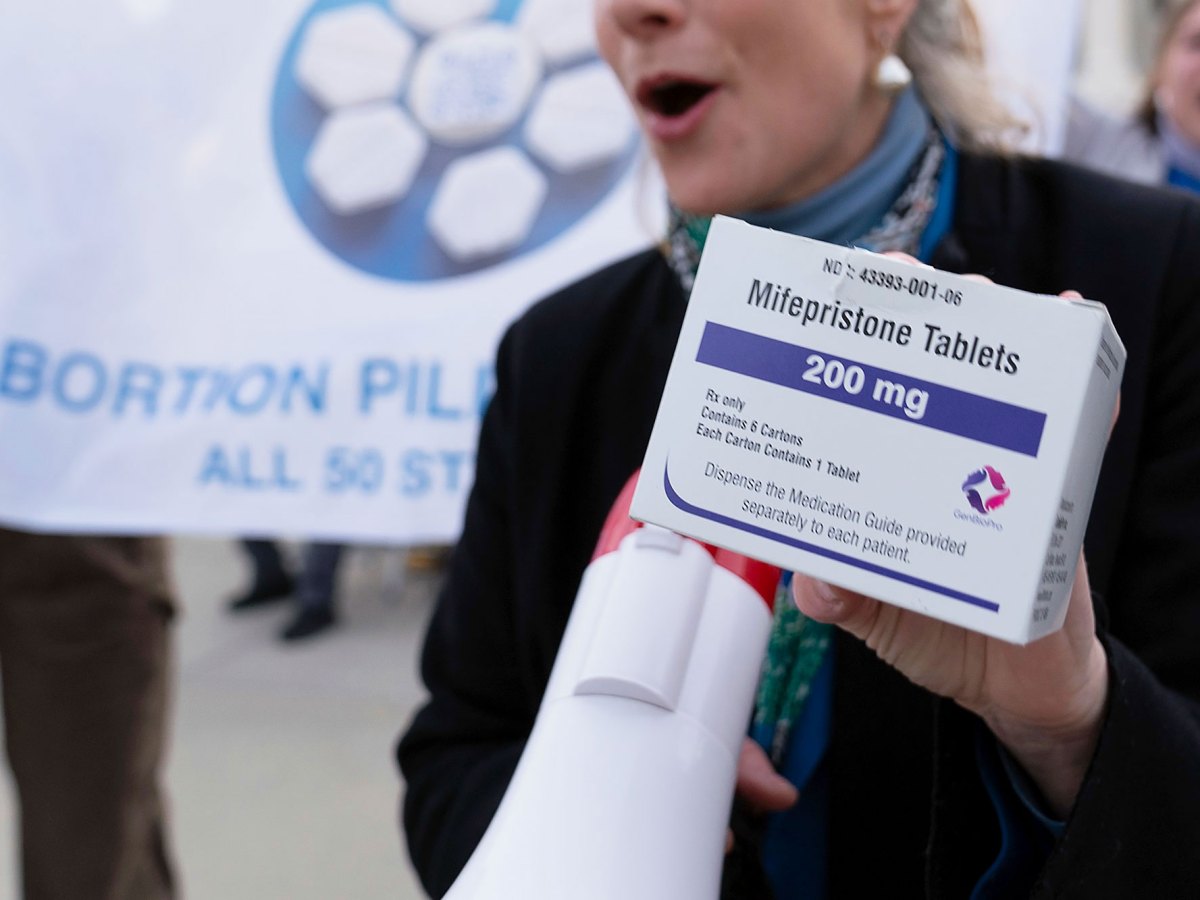 A hand holds up a box of Mifepristone Tablets