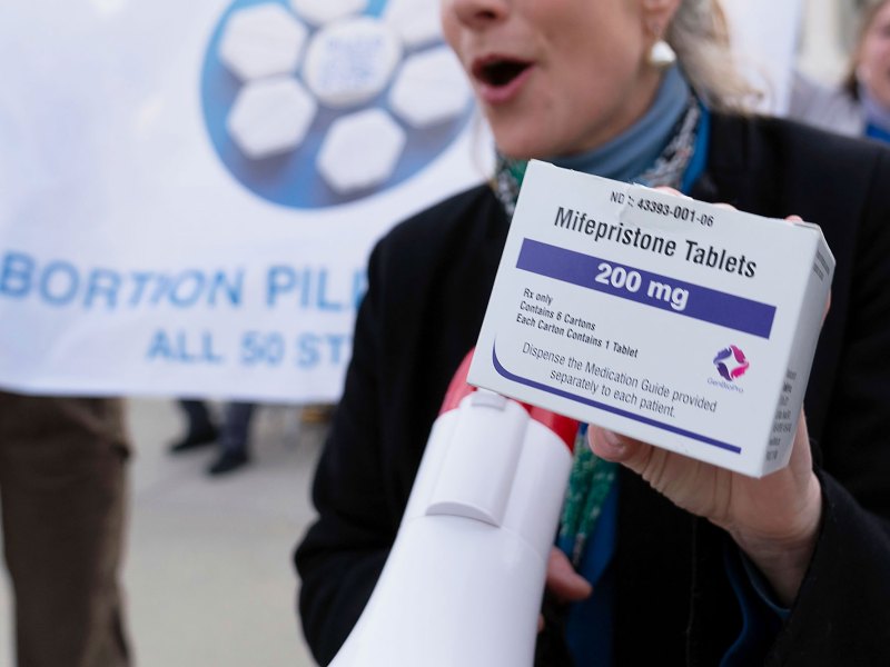 A hand holds up a box of Mifepristone Tablets