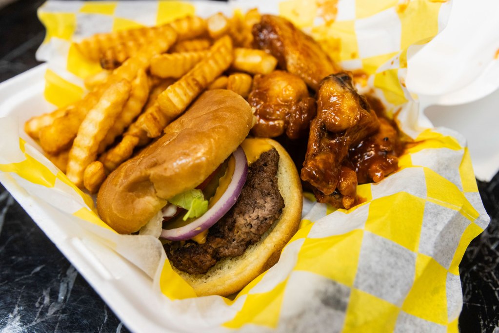 Burgers, wings, and fries plate at a restaurant.