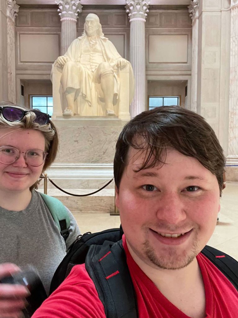 Two people take a selfie in front of a monument