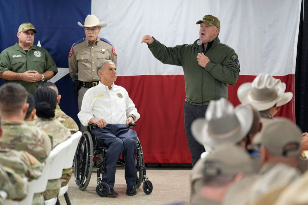 Texas Governor Greg Abbott looks at incoming U.S. Border Czar Tom Homan during a speech