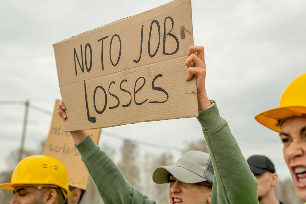 People hold up signs, one reads "No to job losses"