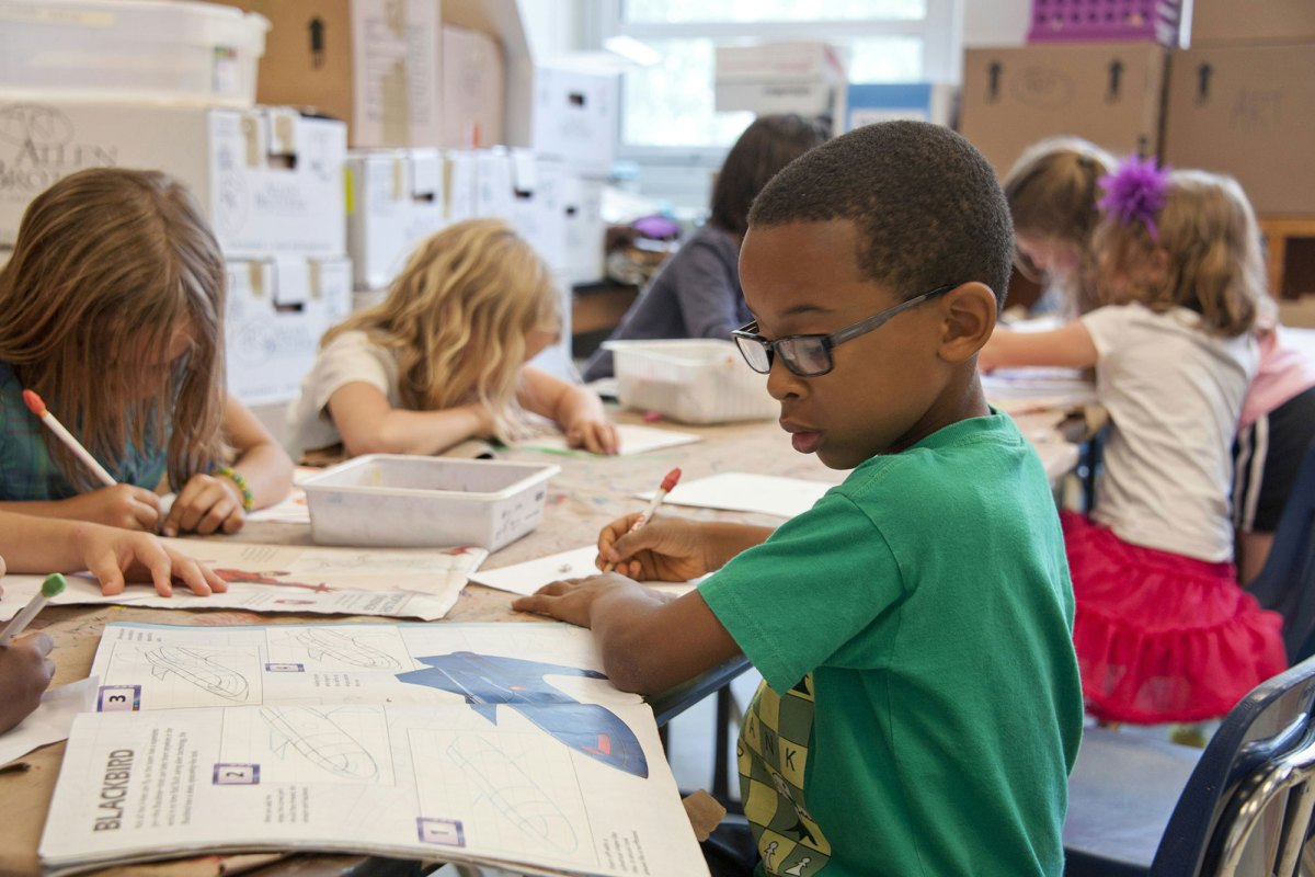 Young boy in green shirt writing in a classroom