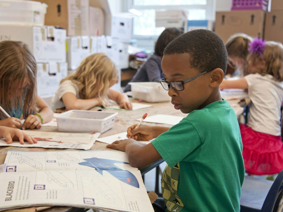 Young boy in green shirt writing in a classroom