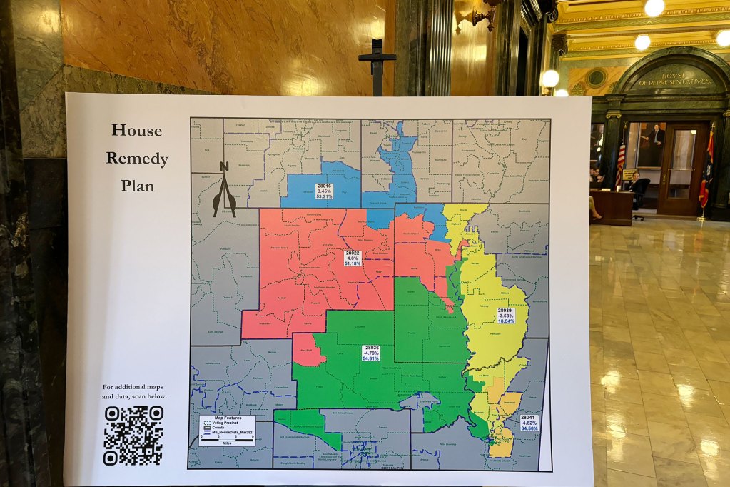 A large poster on an easel in a hallway with colorful county maps, labeled "House Remedy Plan"