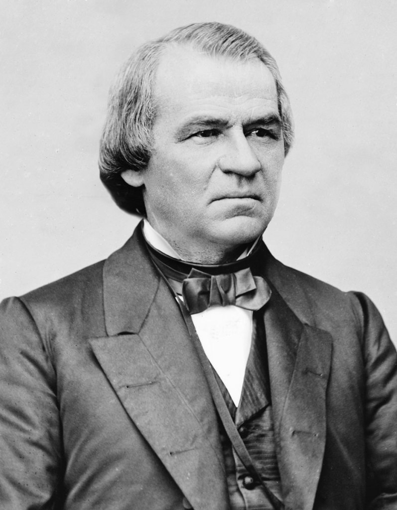 A black and white photo portrait of a man in a formal suit, vest and bowtie