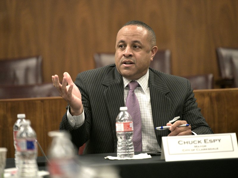 A man in a pin striped suit sits behind a card that reads Chucky Espy Mayor City of Clarksdale
