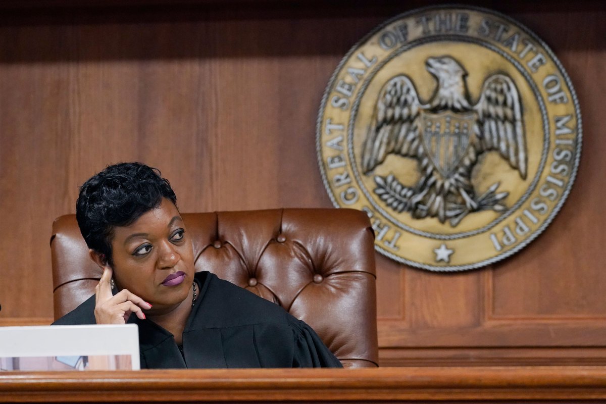 A judge sits at her desk. The Seal of the State of Mississippi hangs behind the chair.