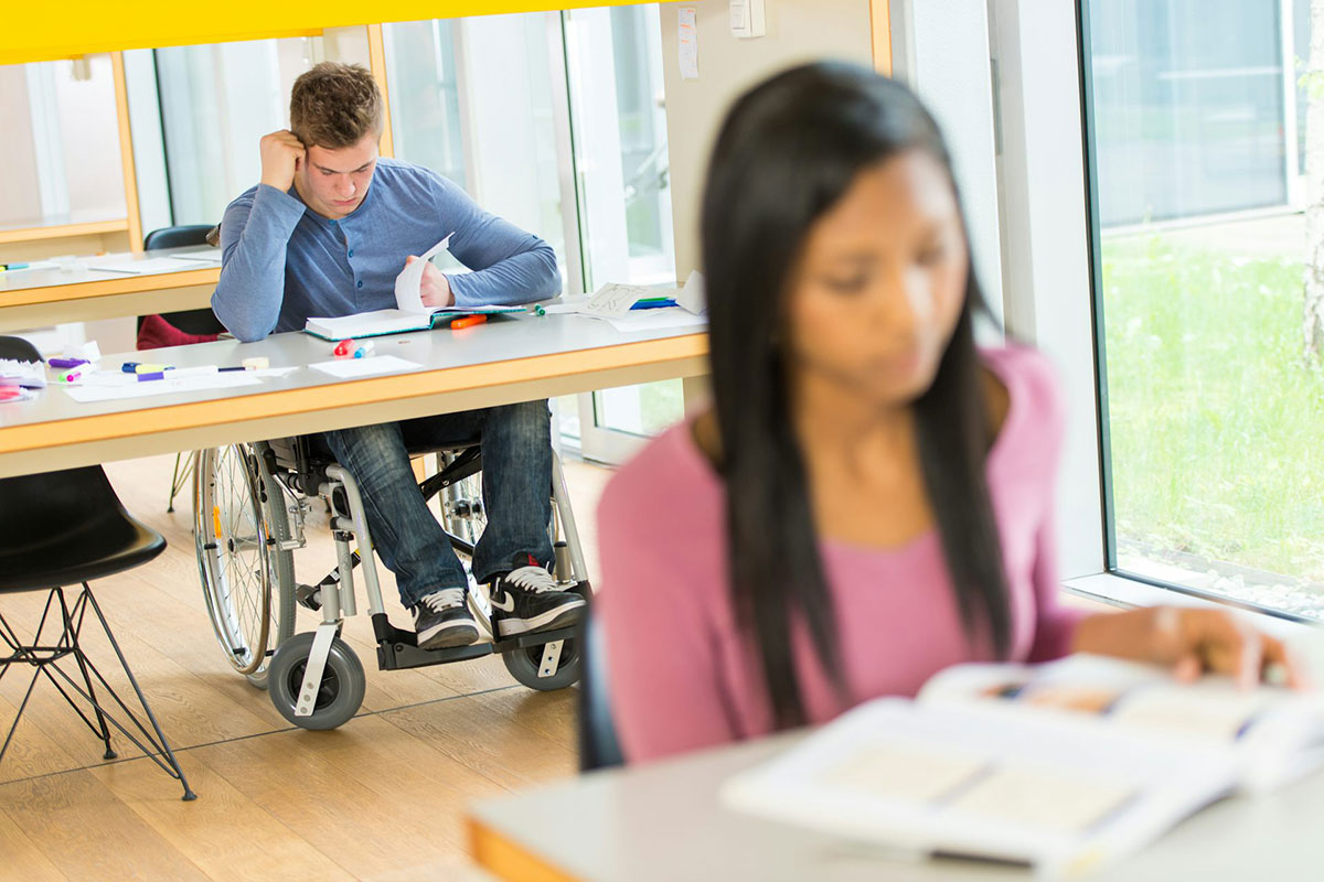 Students sit in a classroom reading, one is in a wheelchair