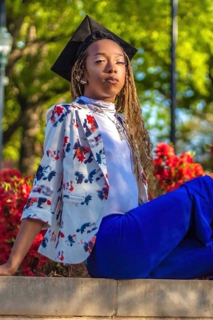 A photo of Jay Lee sitting wearing a graduation cap.