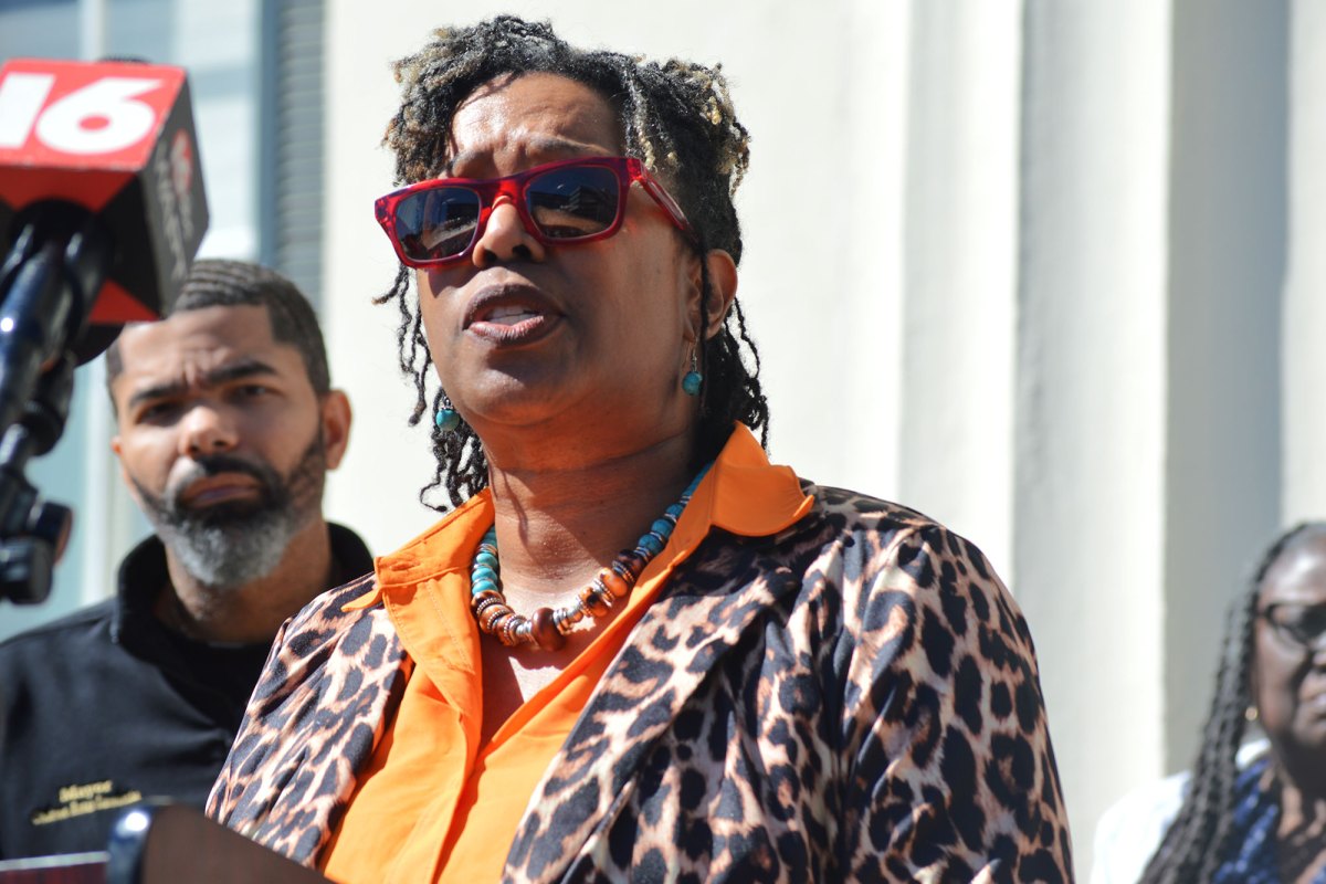A woman in a leopard print top speaks at a press conference