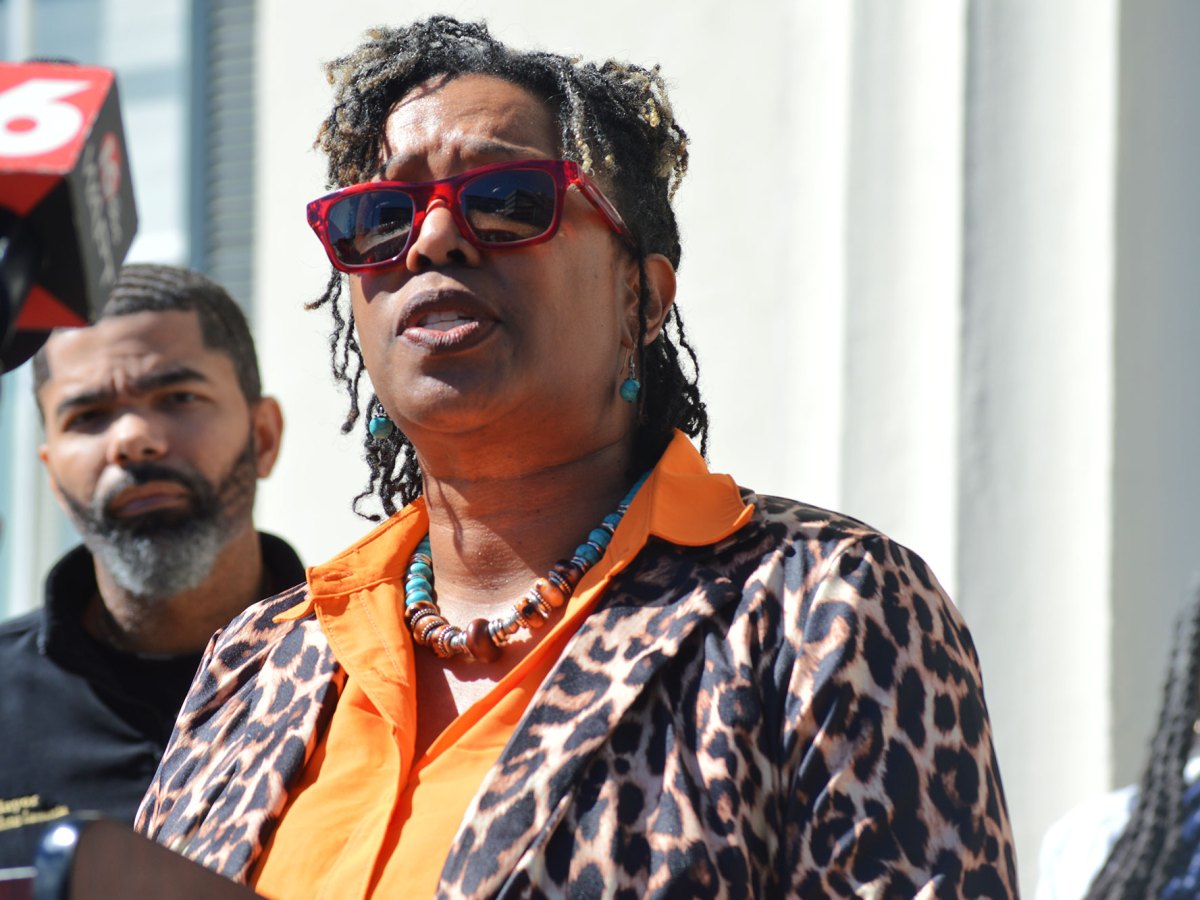 A woman in a leopard print top speaks at a press conference