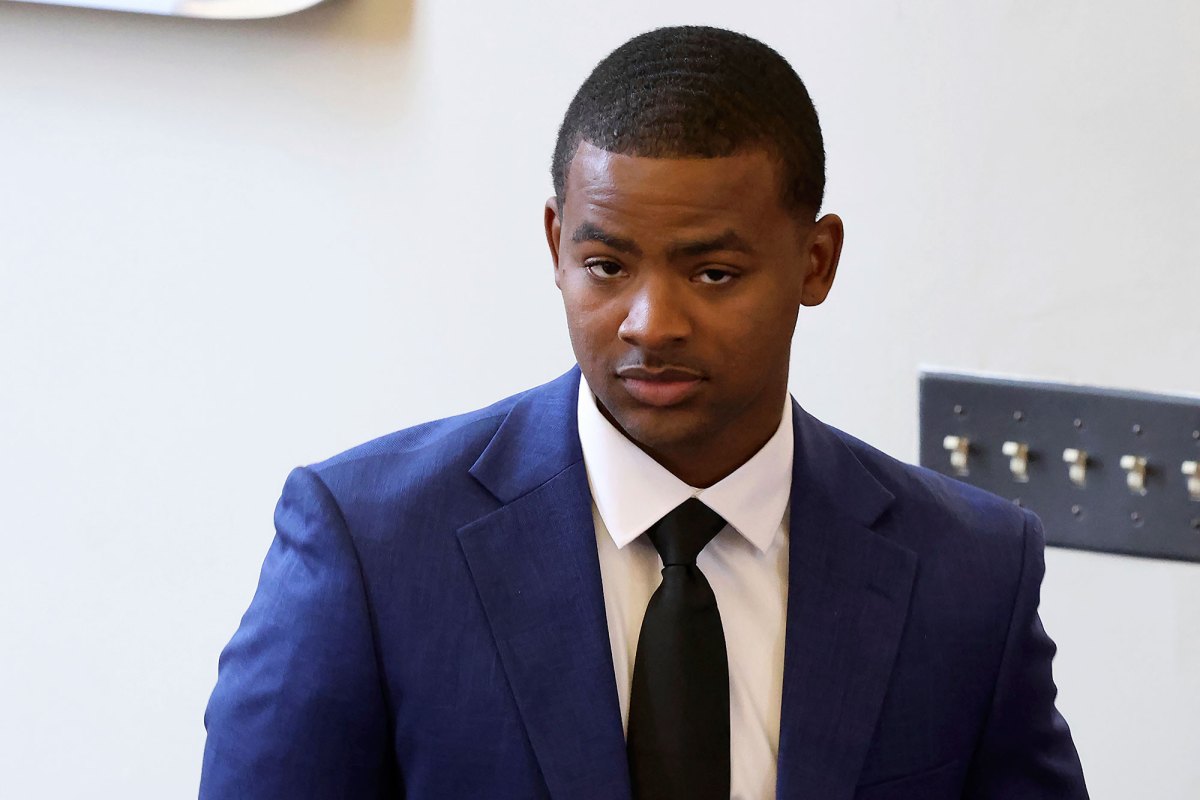 A man in a navy suit and dark tie indoors