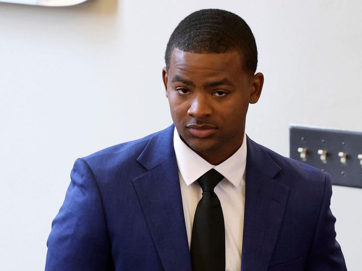 A man in a navy suit and dark tie indoors