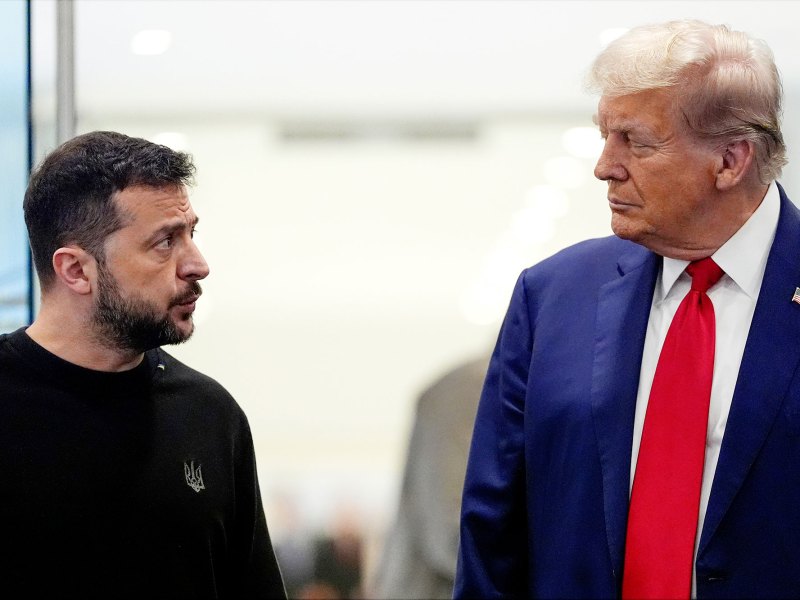 Two presidents look at each other, one in casual black attire and the other in a suit