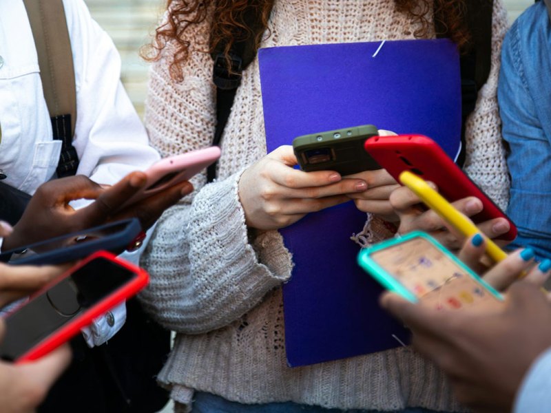 Close up of a several teens hands holding colorful smartphones