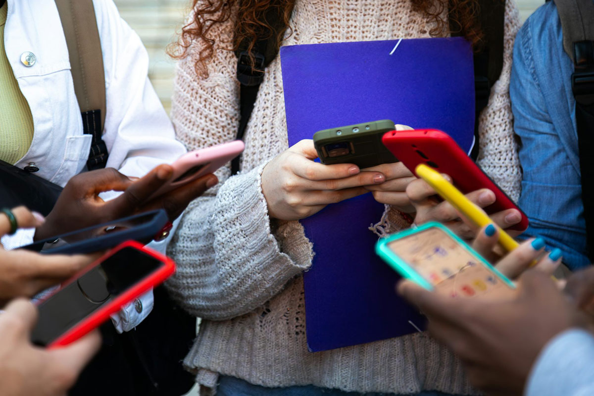 Close up of a several teens hands holding colorful smartphones