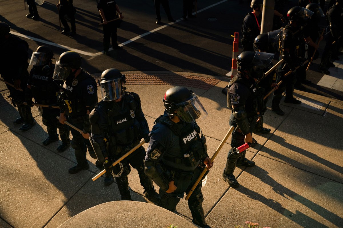 Policemen standing on a street with sticks in their hands.