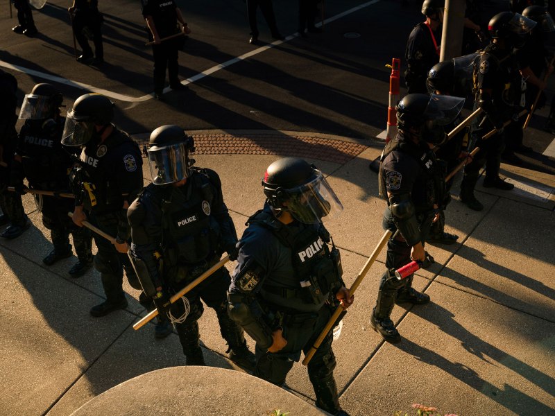 Policemen standing on a street with sticks in their hands.